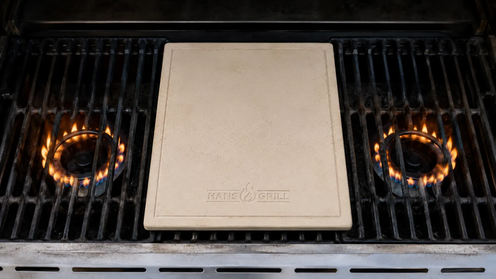 Close-up of a pizza stone on a grill grate with a burner off directly beneath it for indirect heat